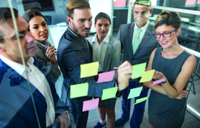 Eine Gruppe von Geschäftsleuten gemischten Alters sitzt im Büro und arbeitet an innovativen Geschäftsideen.