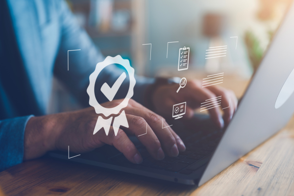 Eine Person arbeitet konzentriert am Laptop, begleitet von digitalen Prüf- und Dokumentensymbolen, symbolisch für Qualität und Compliance