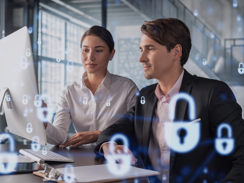 Zwei Business-Experten analysieren gemeinsam Daten am Computer, Symbolik für IT-Sicherheit und Cybersecurity