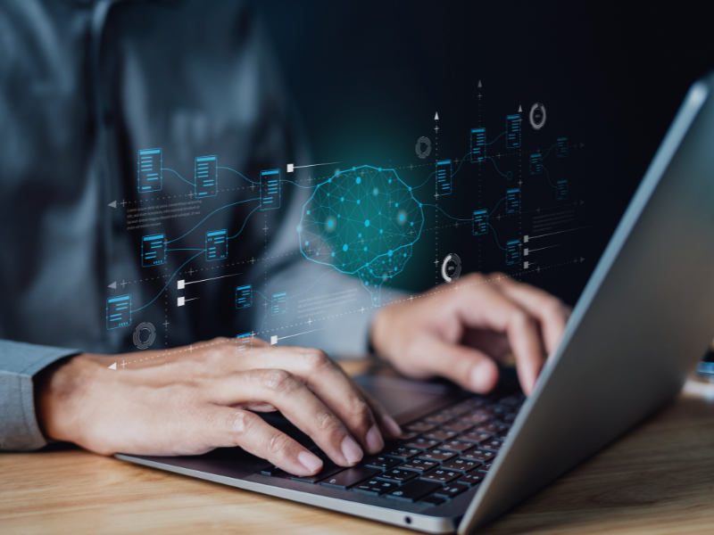 Person arbeitet am Laptop mit visualisiertem KI-Netzwerk und Datenflüssen, symbolisch für Skalierbare KI-Lösungen für die Automobilbranche