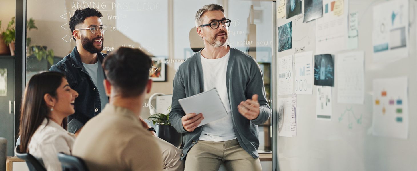 Team diskutiert Ideen vor einem Whiteboard mit Skizzen und Notizen, symbolisch für IT-Projektmanagement