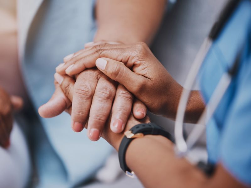 Medizinisches Personal hält Hand von Patient, symbolisch für Fundraising in Kliniken