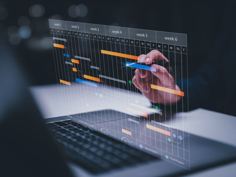 Hand bearbeitet einen digitalen Projektzeitplan auf einem transparenten Diagramm, symbolisch für Software zur Projektsteuerung