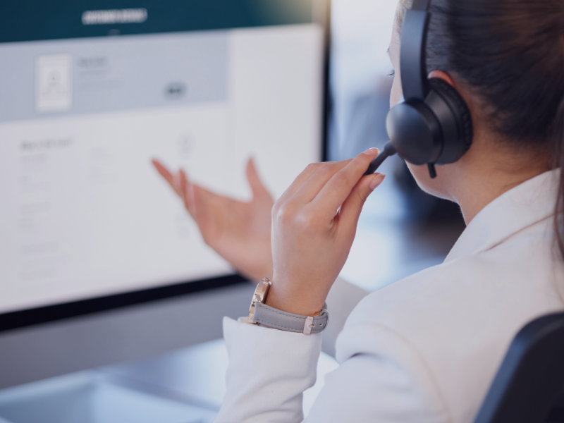 Frau im Büro mit Headset auf im Gespräch, symbolisch für CRM für Stadtwerke