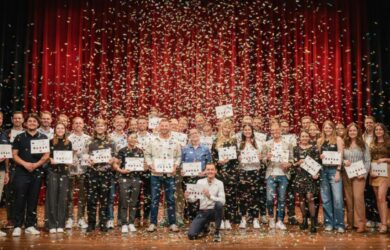 Große Gruppe von Menschen hält Zertifikate auf einer Bühne mit Konfetti, symbolisch für Weiterbildung und Consileons KI Führerschein