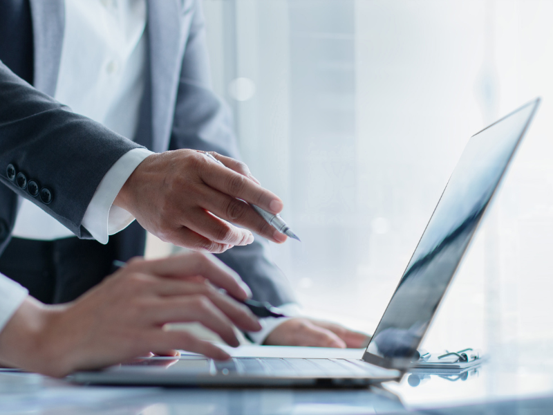 Kollegen besprechen Informationen auf Laptop, symbolisch für CRM für Banken