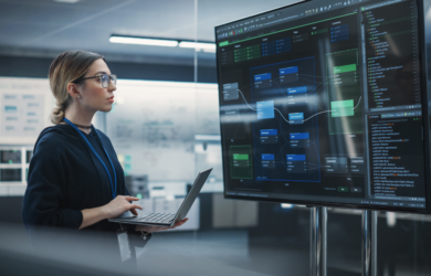 Person analysiert Software-Architektur und Code auf großen Monitoren, symbolisch für digitale Entwicklung