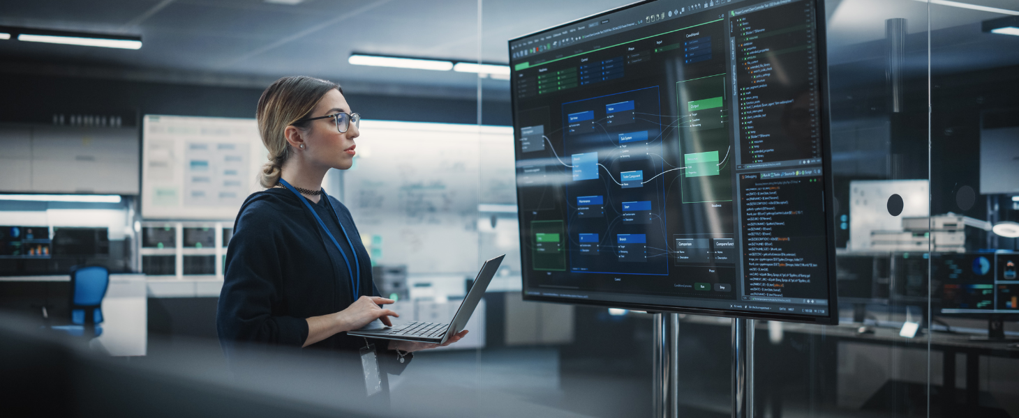 Person analysiert Software-Architektur und Code auf großen Monitoren, symbolisch für digitale Entwicklung
