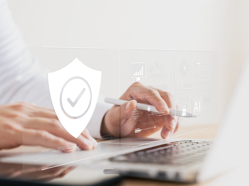 Hand die am Laptop arbeitet mit IT-Symbolen, symbolisch für Datensicherheit bei KI-Pharmaaudits