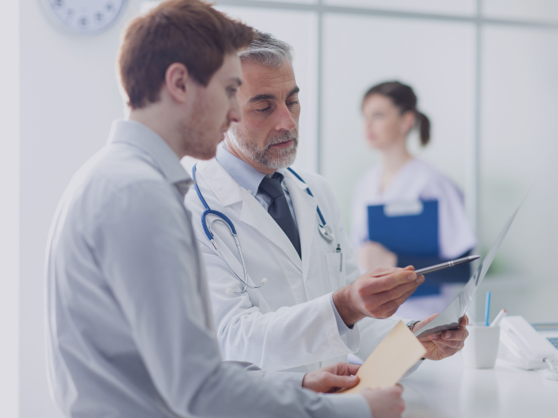 Arzt im Gespräch mit Berater, symbolisch für regulatorische Beratung für Krankenhäuser
