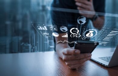 Person nutzt Smartphone und Laptop, darüber eingeblendete digitale Diagramme und Finanzkennzahlen, symbolisch für datengetriebene Analyse, digitale Geschäftsmodelle und moderne Finanztechnologie.