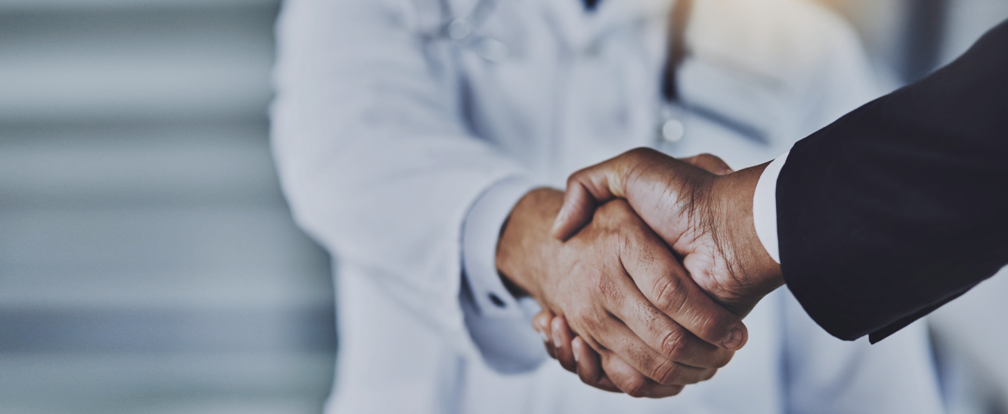 Zwei Personen in Business und Arztbekleidung geben sich die Hand, symbolisch für erfolgreiche Zusammenarbeit von Consileon im Healthcare Geschäftsbereich.
