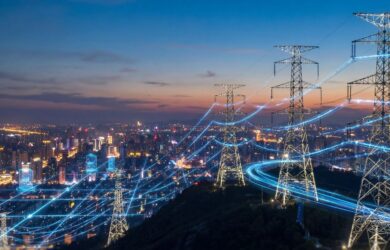 Hochspannungsmasten über einer beleuchteten Stadt bei Nacht, durchzogen von leuchtenden Datenlinien, symbolisch für intelligente Energienetze, Digitalisierung und vernetzte Infrastruktur.