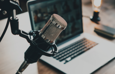 Mikrofon vor Laptop in einer Arbeitsumgebung, symbolisch für digitale Kommunikation und Podcasts