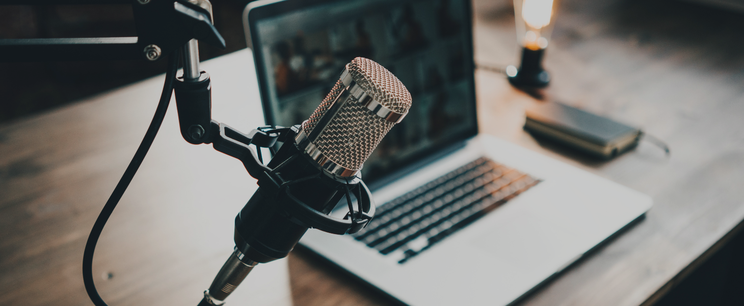 Mikrofon vor Laptop in einer Arbeitsumgebung, symbolisch für digitale Kommunikation und Podcasts