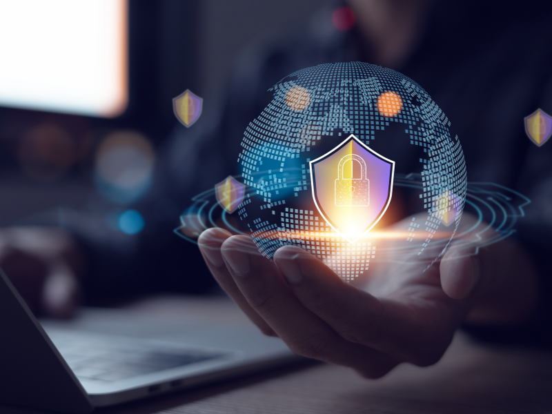 Hand hält digitale Weltkugel mit Schloss- und Sicherheitssymbolen, symbolisch für globale IT-Sicherheit und Datenschutz